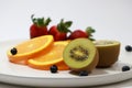 Cut in half of kiwi fruit put together with out focus The thin round pieces of orange slices, strawberry and blueberry on the Royalty Free Stock Photo