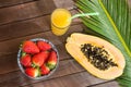 Cut in Half Ripe Papaya Fresh Strawberries Tropical Juice in Tall Glass with Straw. Palm Leaf on Plank Wood Table in Cafe Royalty Free Stock Photo