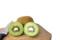 Cut half and whole ripe kiwi fruit with knife on wooden cutting board on white background. Royalty Free Stock Photo