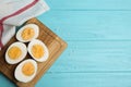 Cut hard boiled chicken eggs on blue wooden table, flat lay. Space for text Royalty Free Stock Photo