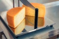 Cut head of cheese on an industrial cutter in a cheese factory. Packing of Gouda cheese on dairy