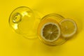 Cut lemon in glassware on yellow backgroundCopy space