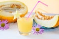 Cut melon in half next pieces of melon on a plate glass of smoothie with a straw of melon and autumn flowers asters Royalty Free Stock Photo