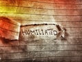 On a cut notebook page the word humiliated written