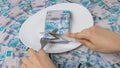 Cut off piece of money in a plate with a knife. Tenge, Kazakhstan. Concept, living wage. Economy, Central Asia. Sawing the budget