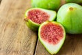 Cut open halved ripe green fig with red pulp. Aged plank wood background. Copy space