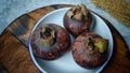 Cut open too ripe mangosteens against rustic white background