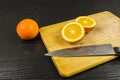 The orange is cut in half on a chopping board.