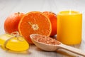 Cut orange with two whole oranges, soap, wooden spoon with yellow sea salt and burning candle Royalty Free Stock Photo