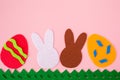 Cut out of felt applications of eggs and white and brown rabbits on the grass. Pink background. Flat lay. Easter holiday. Copy Royalty Free Stock Photo