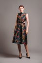 Cut out waist midi dress in floral embroidery with black high heels. Ginger lady posing in studio