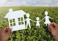 Cut outs house and family in hands over landscape