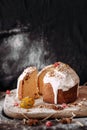 Cut panetone piece on a wooden table crushed with flour. Painted quail egg. Black background