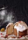 Cut panetone piece on a wooden table crushed with flour. Painted quail egg. Black background