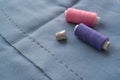 Cut part of skirt with a sewn tuck, thimble and two spools of thread. Two spools of pink and purple threads and tailor tool are