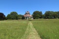 A cut path in the grass meadow leads to an unusual historic sixteen sided house on a beautiful sunny summers day in Devon, England Royalty Free Stock Photo