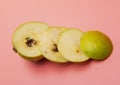 Cut pear with a worm on a pink background