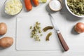 Cut pickled cucumbers near ingredients on white wooden table, flat lay. Cooking vinaigrette salad