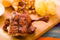 Cut pieces cooked guine pig meat lying on wooden surface next to potatoes, tostados and bowl of salsa Royalty Free Stock Photo