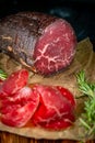 Cut into pieces smoked bresaola on a cutting Board. Italian antipasti prosciutto