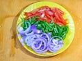 Cut pieces of tomato, capcicum and onion on a same yellow plate