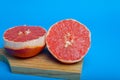 Cut pink grapefruit isolated on blue background. Royalty Free Stock Photo