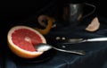 A cut pink grapefruit with a knife and a spoon on a dark surface Royalty Free Stock Photo