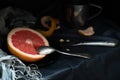 A cut pink grapefruit with a knife and a spoon on a dark surface Royalty Free Stock Photo