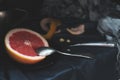 A cut pink grapefruit with a knife and a spoon on a dark surface Royalty Free Stock Photo