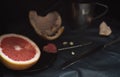 A cut pink grapefruit with a knife and a spoon on a dark surface Royalty Free Stock Photo