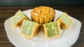 Cut quartered pandan mooncake and one pandan mooncake, wood background.