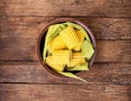 Cut raw corn in ceramic plate with leaves on rustic wood textured table. Healthy summer food concept. Fresh uncooked corn. Clean Royalty Free Stock Photo