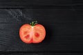 Cut red tomato on a black wooden background, food photography Royalty Free Stock Photo