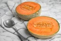 Cut ripe cantaloupe melon and spoon on marble table Royalty Free Stock Photo