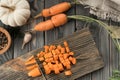 Cut ripe raw orange carrot into cubes on kitchen wooden board. Diced carrot with knife. Flat lay view. Healthy food.
