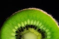 Cut slice of kiwi fruit close-up on black background horizontal.