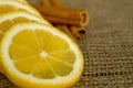 Cut on a slice of lemon on burlap close-up with cinnamon