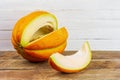 A cut slice from ripe sweet yellow melon on a wooden table on a white wooden background with a copy space. Royalty Free Stock Photo