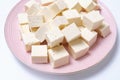 Cut tofu cubes on a pink plate on a white background close-up. Royalty Free Stock Photo