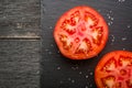 Cut tomato red with seeds and patterns. View from above. Black stone slate background. Royalty Free Stock Photo