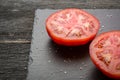 Cut tomato red with seeds and patterns. View from above. Black stone slate background. Royalty Free Stock Photo