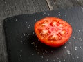 Cut tomato red with seeds and patterns. View from above. Black stone slate background. Royalty Free Stock Photo