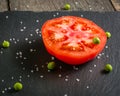 Cut tomato red with seeds and patterns. View from above. Black stone slate background. Royalty Free Stock Photo