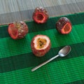 Cut top of one full passionfruit and three empty fruits with a spoon at side on bamboo mats Royalty Free Stock Photo