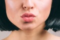 Cut view of beautiful lips with lipstick on. Young brunette with bob haircut. Kiss. Naked neck. Isolated on light studio