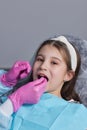 Cut view hands in latex gloves to floss child front teeth. Woman hold dental tools beside.