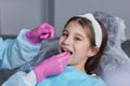 Cut view hands in latex gloves to floss child front teeth. Woman hold dental tools beside.