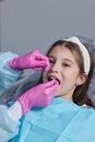 Cut view hands in latex gloves to floss child front teeth. Woman hold dental tools beside.