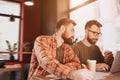 Cut view of two hipsters studying in cafe. One of them is working on computer while another one is lookint at what his Royalty Free Stock Photo