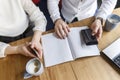 Cut view of woman`s and man`s hands holding phones. Guy is holding pen in hand on journal. They wear suits. Also there are a cup Royalty Free Stock Photo